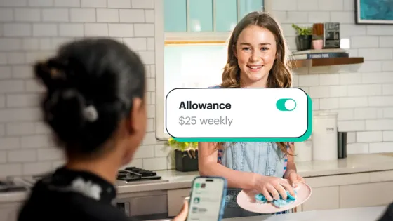 Young girl cleaning dishes while smiling at her parents who on the phone with a pop-up saying "Allowance $25 weekly" toggled on