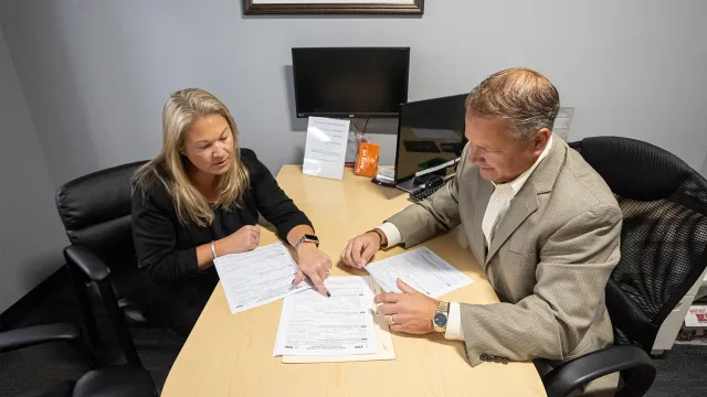 A North Easton Savings Bank lender and customer sitting across from each other at a desk and looking over paperwork together