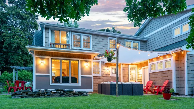 A backyard with a patio and large lawn in the evening
