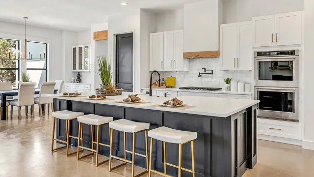 A large kitchen with white cabinets, white countertops, and an island with dark grey cabinets