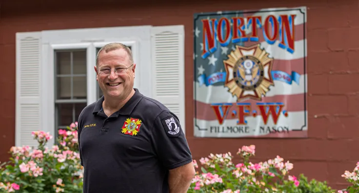 A North Easton Savings Bank local business partner smiling in front of a building with a sign that says, "Norton V.F.W."