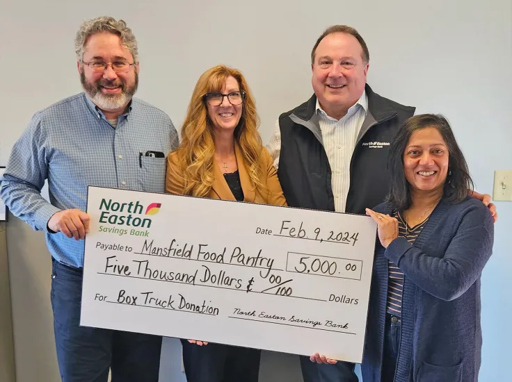 North Easton Savings Bank lenders and Mansfield Food Pantry employees holding a large check that says, Data: Feb 9, 2024, Payable to: Mansfield Food Pantry 5,000 dollars For: Box Truck Signature: North Easton Savings Bank