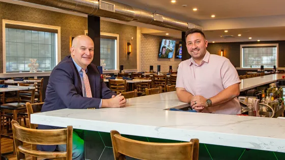 A North Easton Savings Bank lender sitting at a bar next to a local business partner standing behind the bar in a tavern