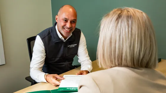 North Easton Savings Bank lender smiling and sitting across from a customer at a desk and holding a paper